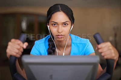 Buy stock photo Shot of a young ethnic woman working out in the gym on a stationary bike