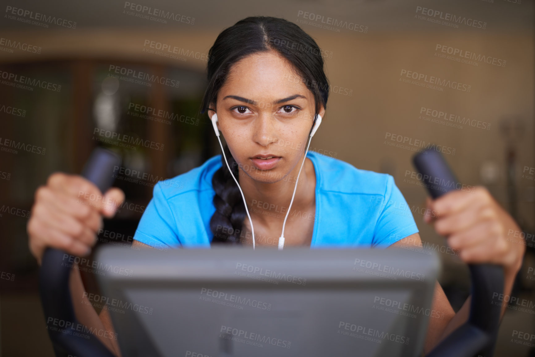 Buy stock photo Shot of a young ethnic woman working out in the gym on a stationary bike