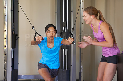 Buy stock photo A young woman working out at the gym with her friend