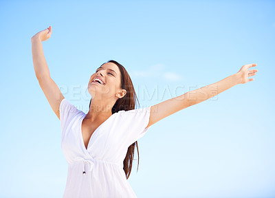 Buy stock photo A carefree young woman standing with her arms outstretched against a blue sky