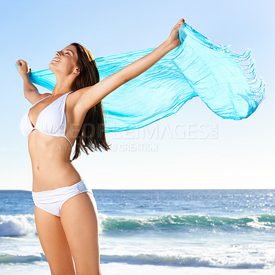 Buy stock photo A beautiful young woman holding a sarong that's blowing in the wind