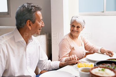 Buy stock photo Senior couple, dinner and holding hands in home dinning room, praying and gratitude for meal. Grace, smile and love at thanksgiving lunch, retired and elderly people enjoying family time in America 