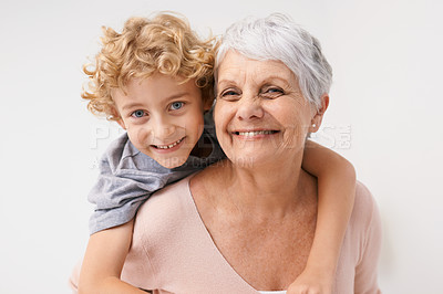 Buy stock photo Piggyback, portrait and grandmother with child embrace, happy and bonding against a wall background. Love, face and senior woman with grandchild having fun, hug and enjoying the weekend together