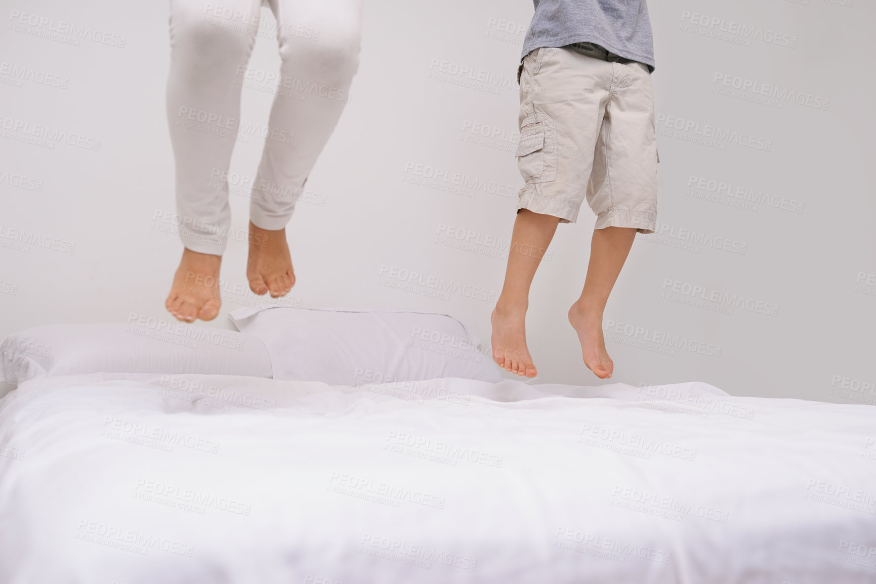 Buy stock photo Jumping, bed and kids with legs, energy and morning in a bedroom with game and feet. Youth, sibling and home with a excited child on duvet in air with crazy play, leap and fun in house with friends