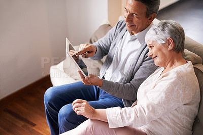 Buy stock photo Shot of a senior couple looking at the screen of a digital tablet