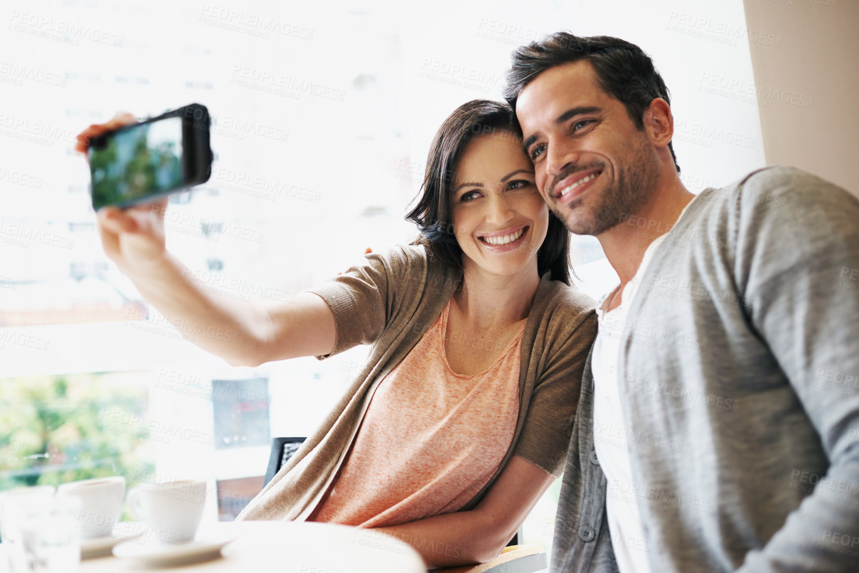 Buy stock photo Happy couple, selfie and love in coffee shop on vacation and post on social media of espresso date. Man, woman and bonding in restaurant on profile picture and romantic memory on smartphone gallery