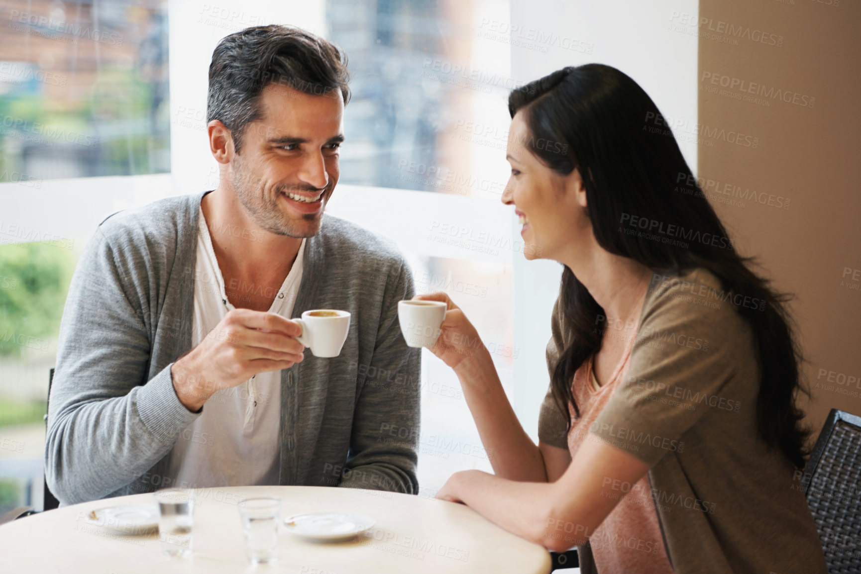 Buy stock photo Love, conversation and couple with coffee on date for romance or anniversary in cafeteria. Happy, bonding and young man and woman talking and drinking latte, espresso or cappuccino at restaurant.