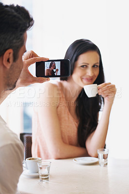 Buy stock photo Shot of a man taking a snapshot of his wife with his phone at a cafe