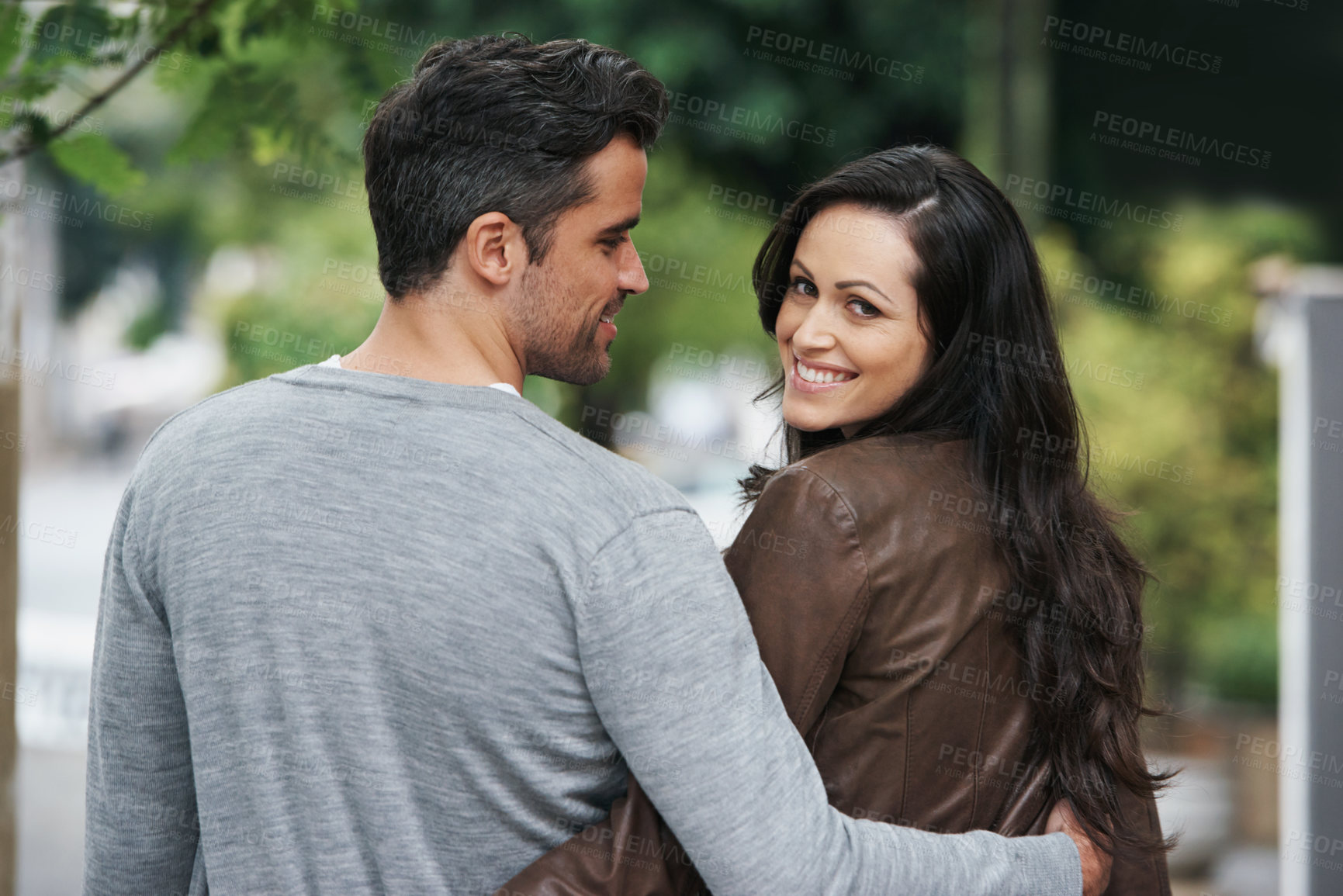 Buy stock photo Shot of an affectionate young couple walking in the street