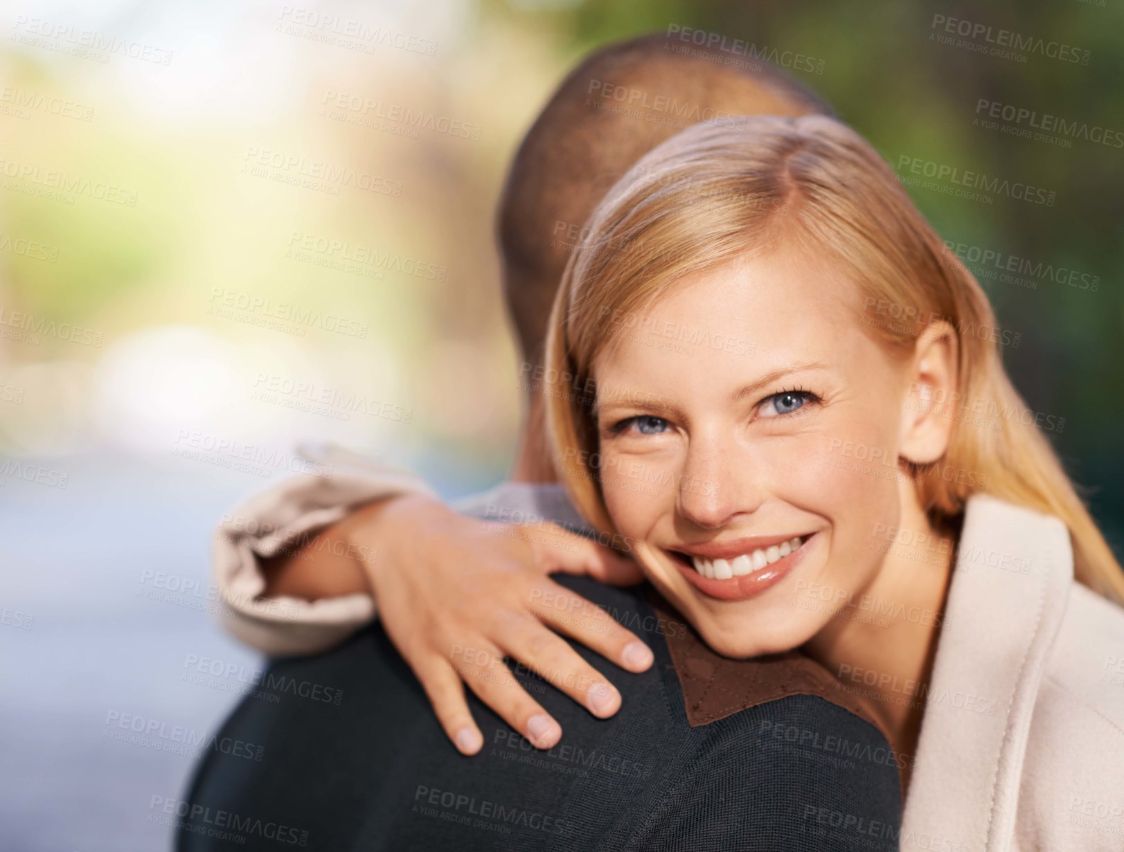 Buy stock photo Shot of a young woman embracing her boyfriend in the outdoors