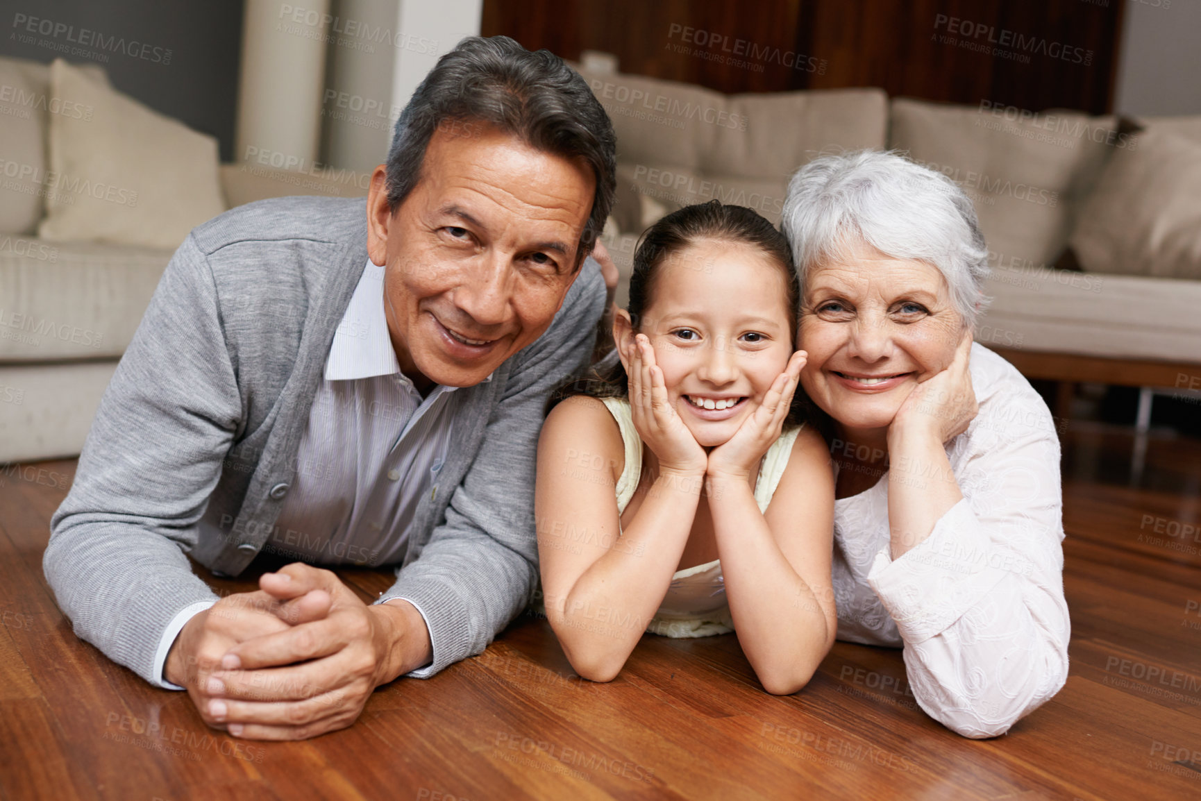 Buy stock photo A girl lying down and smiling at the camera with her grandparents