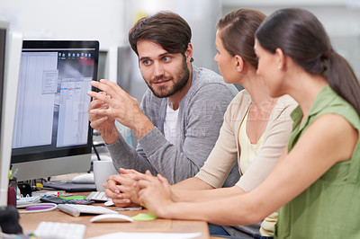 Buy stock photo Shot of a group of young businesspeople talking at their desk