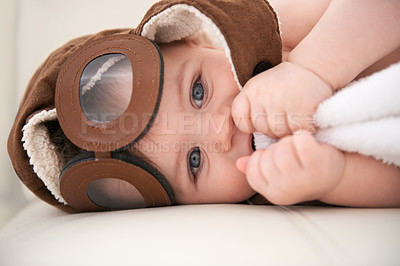 Buy stock photo Baby, portrait and pilot hat or happy at home on bed for childhood development for growth, blanket or comfortable. Kid, boy and face airplane flying accessory in apartment for peace, relaxing or rest