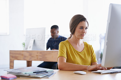 Buy stock photo A young woman working at her desk with her colleague in the background