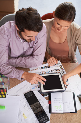 Buy stock photo Shot of young design professionals using a digital tablet while editing images