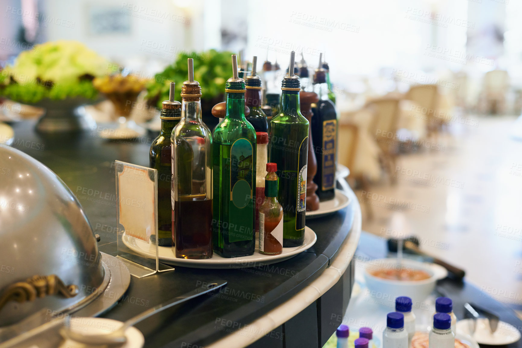 Buy stock photo Sauce, bottles and condiment in restaurant for food with hospitality industry for dining. Catering, cuisine and plate of flavors selection on counter for lunch, dinner or supper meal in cafeteria.