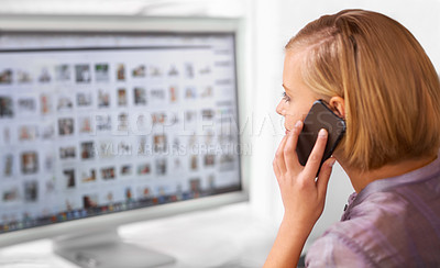 Buy stock photo Shot of a young woman talking on the phone while looking at a computer screen in an office
