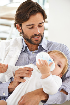 Buy stock photo Bonding, bottle and father feeding baby for child development or growth in living room at home. Love, sweet and young dad holding infant, toddler or kid drinking milk in lounge at modern house.