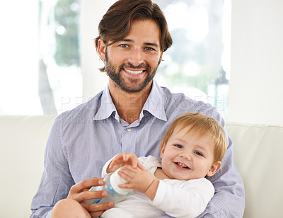 Buy stock photo Cropped view of a father giving his young son a bottle