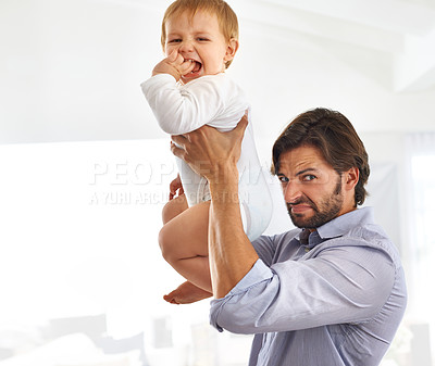 Buy stock photo Shot of a handsome father holding his son up in the air while making a face