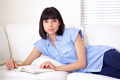 Buy stock photo A young woman reading on the couch