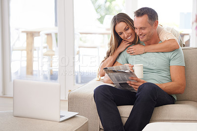 Buy stock photo Cropped shot of a happily married couple reading the newspaper on their sofa