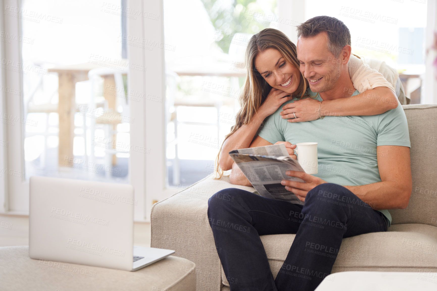 Buy stock photo Cropped shot of a happily married couple reading the newspaper on their sofa