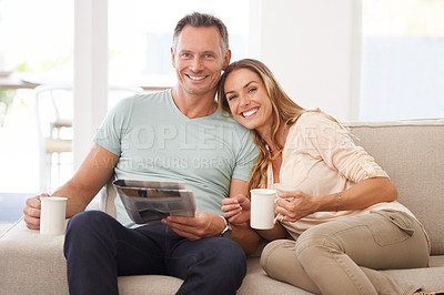 Buy stock photo Portrait of a happily married couple reading the newspaper on their sofa