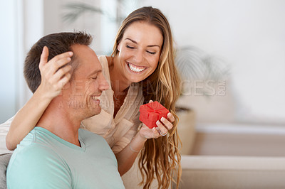 Buy stock photo Wife surprise or present for husband in home and giving on anniversary to celebrate marriage on couch. Woman, love and kindness  with gift for man, romantic and bonding together on sofa with care