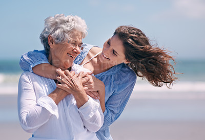 Buy stock photo Shot of a beautiful young woman and her senior mother on the beach