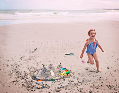 Buy stock photo Portrait, beach and little girl running with sandcastle outdoor by sea or ocean for carefree fun. Nature, water and energy with happy young child playing on sand at coast for holiday or vacation