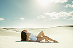 young woman lying on sand and looking at the sky
