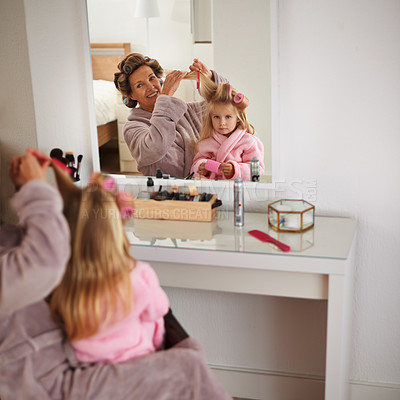 Buy stock photo Mom, daughter and playing with hair in mirror for beauty, care and helping or getting ready. Happy mother, family and girl or kid with rollers for hairstyle, fashion and bonding together at home