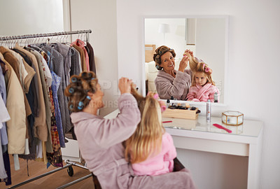 Buy stock photo Mother, daughter and playing with hair in mirror for beauty, care and helping or getting ready. Excited mom, family and girl or kid with rollers for hairstyle, fashion and bonding together at home