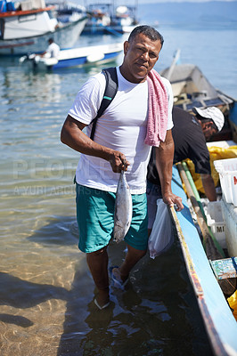 Buy stock photo Portrait of a fisherman standing in the water next to his boat