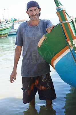 Buy stock photo Portrait of a fisherman standing in the shallow water next to his boat