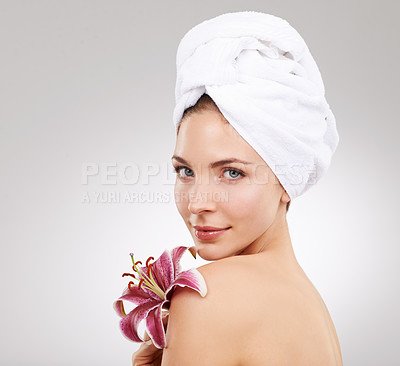 Buy stock photo Cropped studio shot of a beautiful woman holding a flower against her face