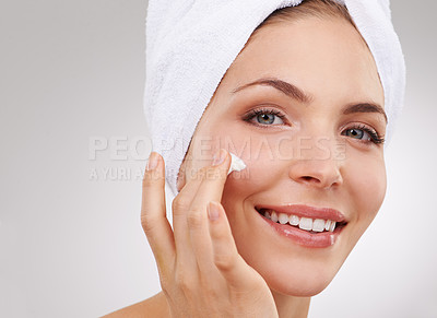 Buy stock photo Cropped studio shot of a beautiful woman rubbing moisturizer on her face
