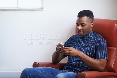 Buy stock photo Man, phone and relax on social media at home, online and internet for website or blogging. Black male person, typing and streaming entertainment on armchair, texting and app for shopping on weekend