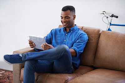 Buy stock photo Man, tablet and relax on social media at home, online and internet for website or blog. Black male person, smile and streaming entertainment on armchair, video call and app for shopping on weekend