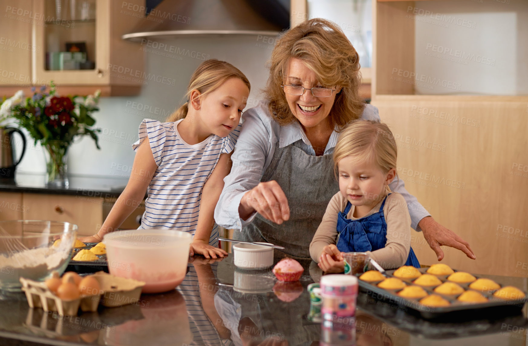 Buy stock photo Grandma, kid and baking with teaching, smile and decorating for cheerful bonding together at home. Happy, pensioner or girl child with cupcake, laugh or icing for creative, playful or fun in kitchen