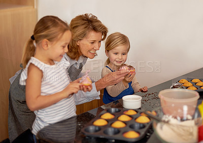 Buy stock photo Grandmother, child and cupcake helping in kitchen or icing  decorations or sprinkles or sweet treat, bonding or teaching. Female person, siblings and baking ingredients or learning, dessert or recipe