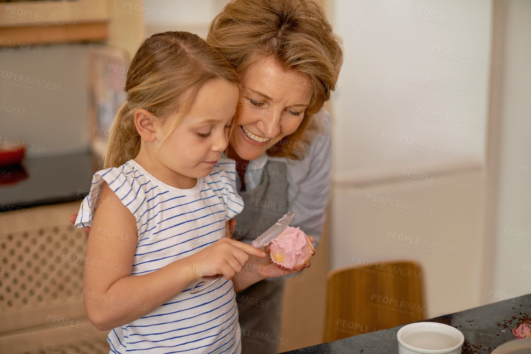 Buy stock photo Woman, child and icing cupcake in kitchen for baking decoration with grandmother, bonding or ingredients. Female person, girl and recipe for sweet dessert at counter or teaching, helping or support