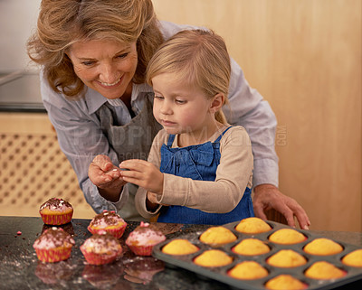 Buy stock photo Grandmother, child and baking cupcakes or decorating with icing or learning creativity, bonding or teamwork. Female person, girl and sweet treats or teaching with ingredients, dessert or sprinkles