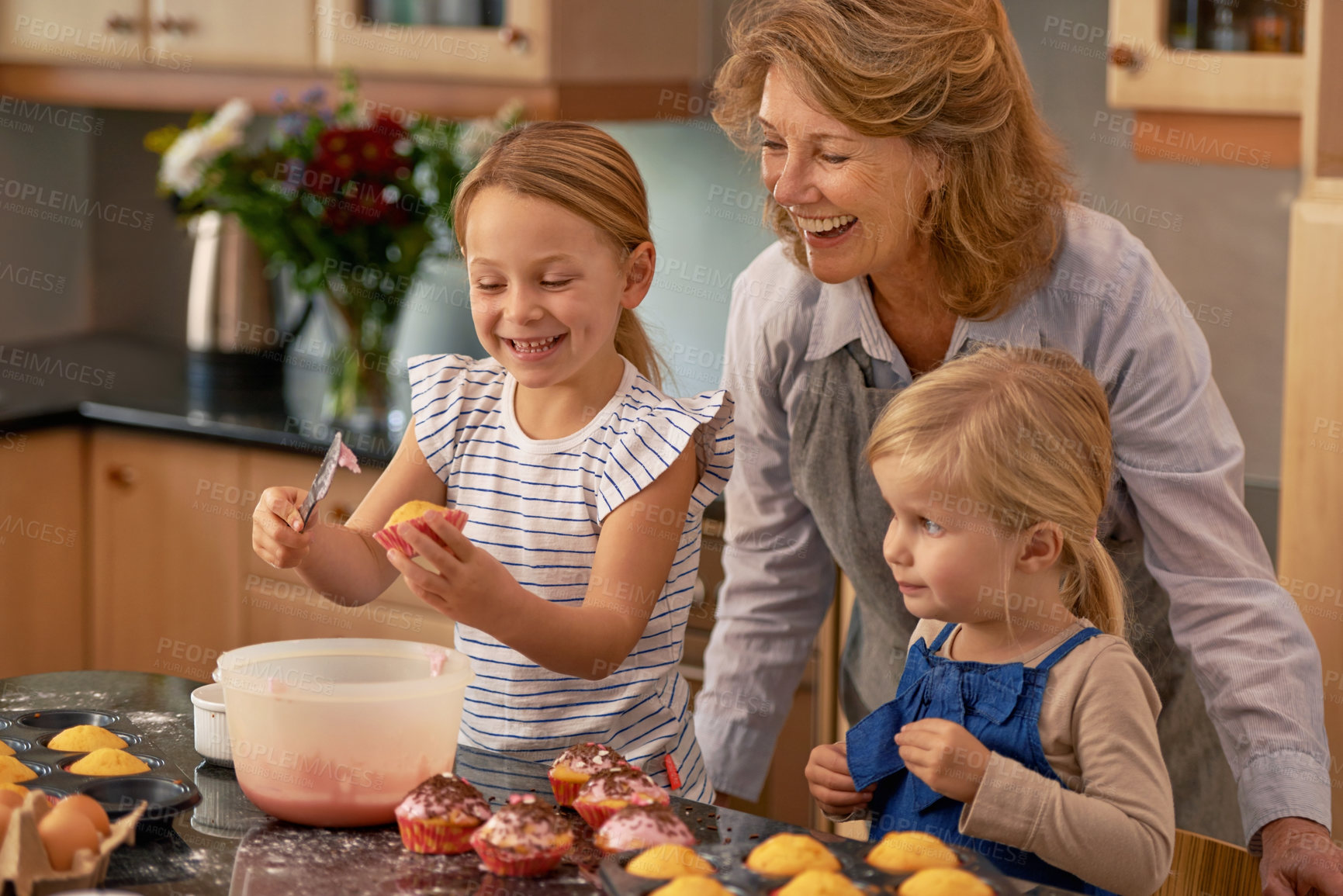 Buy stock photo Mature woman, children and smile for baking in retirement for family, fun and bonding at home. Happy, female pensioner and girl with cupcake, laugh and icing for creative fun together in kitchen