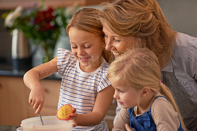 Buy stock photo Shot of two little girls baking cupcakes with their grandmother at home