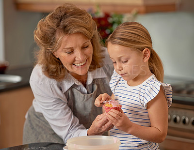 Buy stock photo Elderly woman, child and smile for baking, teaching and bonding together at weekend in family home. Happiness, grandmother and kid with hand, cupcake and icing for playful learning in kitchen