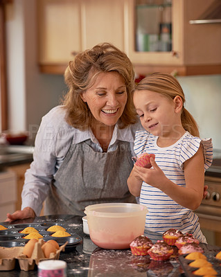 Buy stock photo Elderly woman, girl and smile for teaching, baking and bonding together at weekend in family home. Happy, senior citizen and child with cupcake, ecourage and icing for creative fun in kitchen