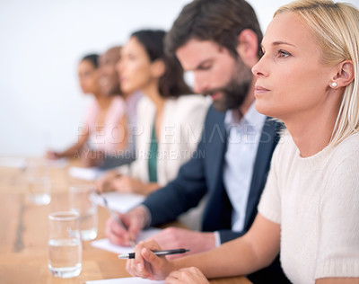 Buy stock photo A group of business people sitting in a row listening to something off camera