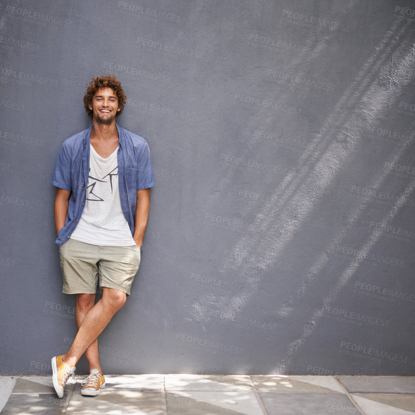 Buy stock photo A handsome young man leaning against a blue/gray wall